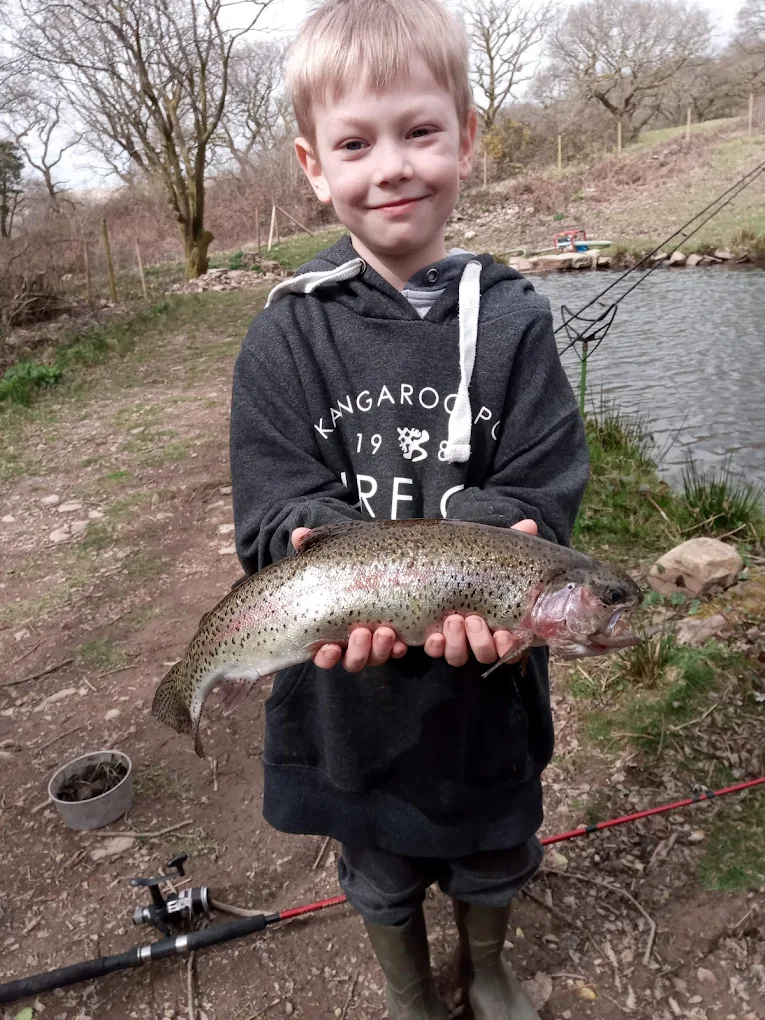 A child holding a trout caught at the lake